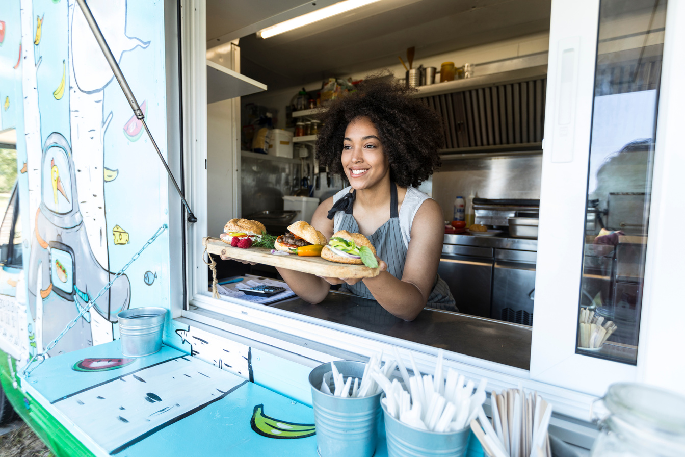 Female food vendor offering burgers in food van